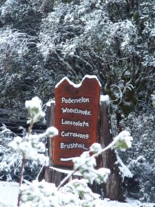 a wooden sign with snow on top of it at Cradle Mountain Highlanders in Cradle Mountain