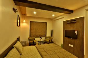 a hotel room with a bed and a television at Hotel Kabir in Ahmedabad