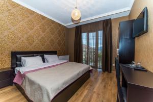 a bedroom with a bed and a desk and a television at Hotel New Telavi in Tʼelavi