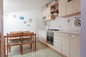 a kitchen with white cabinets and a table and a chair at Apartmani Denis Vela in Podgora