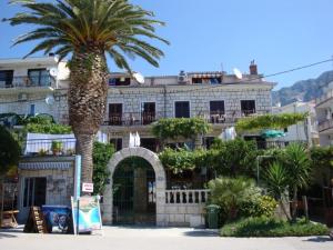 a palm tree in front of a building at Apartmani Denis Vela in Podgora