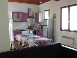 a kitchen with purple cabinets and a table with a vase of flowers at Gite Le Bois Fleuri in Illiers