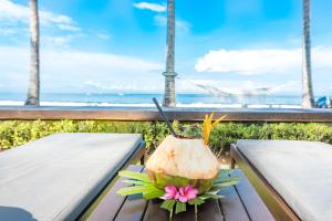 a coconut on a picnic table with the beach in the background at The Chandi Boutique Resort & Spa in Senggigi