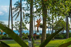 a plant in a park with palm trees and the ocean at The Chandi Boutique Resort & Spa in Senggigi