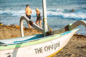 a boat on the beach with people in the water at The Chandi Boutique Resort & Spa in Senggigi