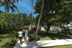 two people walking down a sidewalk in a garden at The Chandi Boutique Resort & Spa in Senggigi
