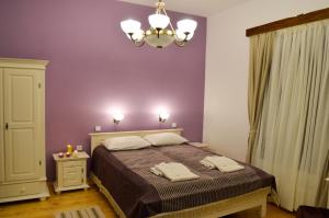 a bedroom with a bed with purple walls and a chandelier at Aronson Villa Tusnad in Băile Tuşnad +67 photos