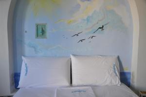 - une chambre avec un lit blanc et des oiseaux volant dans le ciel dans l'établissement Palirroia (High Tide), à Empourios