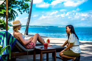 two girls sitting on a couch on the beach at The Chandi Boutique Resort & Spa in Senggigi