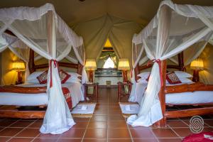 Schlafzimmer mit 4 Betten und Moskitonetzen in der Unterkunft Mbuzi Mawe Serena Camp in Serengeti-Savanne
