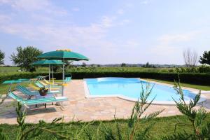 a swimming pool with an umbrella and chairs at Agriturismo Lizzarola in Peschiera del Garda