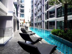 a row of chairs and a swimming pool in a building at Tropical Garden Studio in Pattaya South