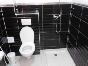 a black tiled bathroom with a toilet and a shower at Bienvenue chez vous in Kenitra