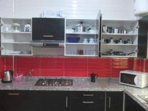 een keuken met rode kasten en een aanrecht bij Bienvenue chez vous in Kenitra