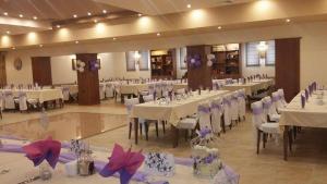 a banquet hall with white tables and chairs and purple bows at Kolhida Complex in Elkhovo