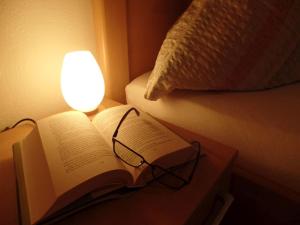 un libro y gafas en una mesa junto a una cama en Stinneshof, en Oberharmersbach