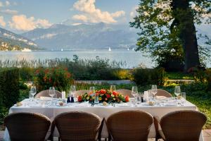 einen Tisch mit einer weißen Tischdecke und Stühlen mit Blick auf das Wasser in der Unterkunft Hotel Seepark Thun in Thun