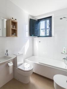 biała łazienka z wanną, toaletą i umywalką w obiekcie Hotel Pazo de Berbetoros w mieście Portomarin