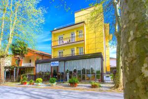 a yellow building with potted plants in front of it at Hotel Majorca in Cesenatico