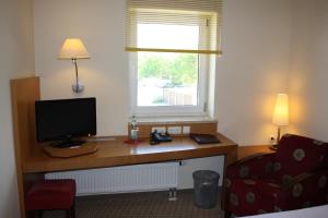 a room with a desk with a television and a window at Pension Geno in Geisenhausen