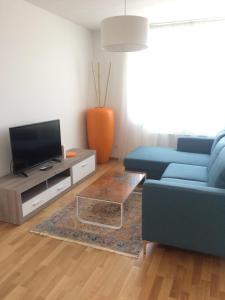 ein Wohnzimmer mit einem blauen Sofa und einem TV in der Unterkunft Vienna Hauptbahnhof Apartments 1 in Wien