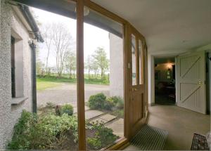 an open door to a porch with a view of a yard at Drum Gatelodge in Bushmills