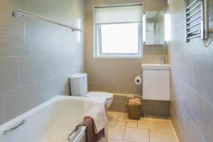 a bathroom with a tub and a toilet and a window at Gwithian Holidays in Hayle