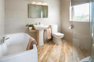 a bathroom with a tub and a sink and a toilet at Gwithian Holidays in Hayle