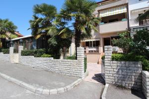 a house with palm trees and a retaining wall at Guest House Aurora in Rovinj