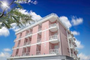 Ein rosafarbenes Gebäude vor blauem Himmel in der Unterkunft Hotel Antoniana in Caorle