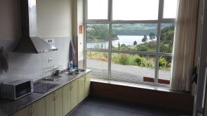 a kitchen with a window with a view of a river at Albergue Ferramenteiro in Portomarin