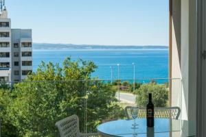 a glass table with a bottle of wine on a balcony at Apartment Morska vila in Split