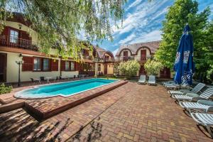 a swimming pool in a courtyard with chairs and an umbrella at Marina Panzio in Si&oacute;fok