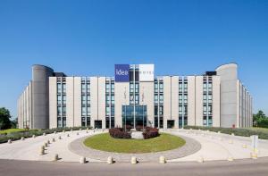 a large white building with a clock in front of it at Idea Hotel Milano San Siro in Milan