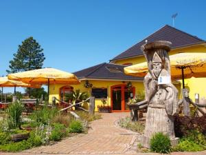 eine Statue vor einem gelben Gebäude mit Sonnenschirmen in der Unterkunft Landhotel zum Honigdieb in Ribnitz-Damgarten