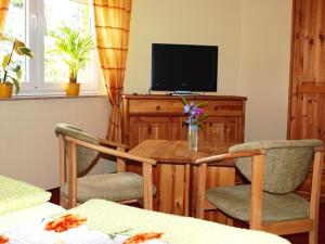 a living room with a table with chairs and a television at Landhotel zum Honigdieb in Ribnitz-Damgarten