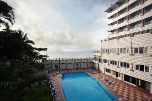 a hotel with a swimming pool next to the ocean at RNS Residency Sea View in Māvalli