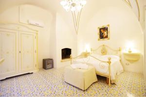 a bedroom with a bed and a chair and a chandelier at Le scuderie di Villa Ravenna Luxury House in Sannicola