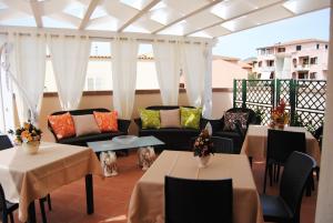 un patio con tavoli e divani su un balcone di B&B Kenzia a Olbia