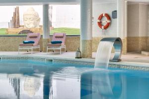 a swimming pool with two chairs and a statue at Cala Millor Garden Hotel - Adults Only in Cala Millor