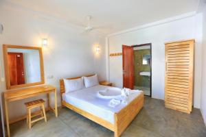 a bedroom with a bed with white sheets and a mirror at Arugambay Roccos in Arugam Bay