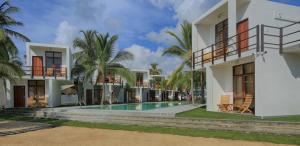a house with a swimming pool and palm trees at Arugambay Roccos in Arugam Bay