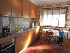 uma cozinha com armários de madeira, uma mesa e uma janela em Oporto Beach House em Arcozelo