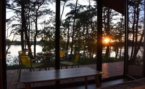 eine abgeschirmte Veranda mit einem Tisch und Stühlen sowie Blick auf den Sonnenuntergang in der Unterkunft Ośrodek Delfin in Ślesin