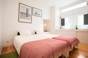 um quarto branco com uma cama grande e um cobertor vermelho em FLH Castelo Cozy Flat em Lisboa