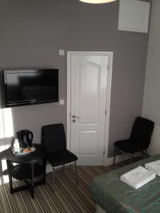 um quarto de hotel com uma cama e cadeiras e uma televisão em Comfotel BLU em Londres