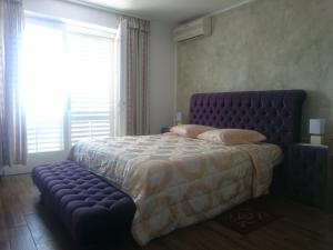 Un dormitorio con una cama grande con un marco de cama de mechón morado en Guest House Vila Luka, en Portorož