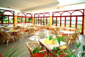 ein leeres Restaurant mit Tischen, Stühlen und Fenstern in der Unterkunft Hotel am Gothensee in Heringsdorf
