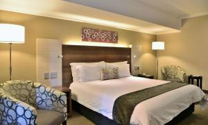 a bedroom with a large bed and two chairs at Birchwood Hotel and OR Tambo Conference Centre in Boksburg