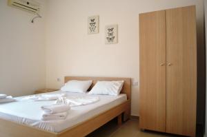 a bedroom with a bed with white sheets and a wooden cabinet at Elite 2 Kosta in Dhërmi +39 photos